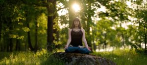 femme en méditation assise sur un rocher dans la nature