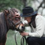 femme tenant la tête d'un cheval et le carressant
