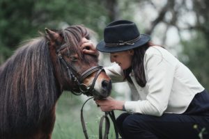 femme tenant la tête d'un cheval et le carressant